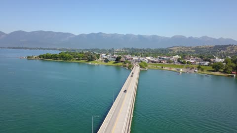Long Bridge Across Mountain Lake Toward Lakeside Town · Sweep