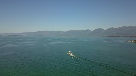 Lone Boat Across a Vast Mountain Lake at Summer · Tracking Shot