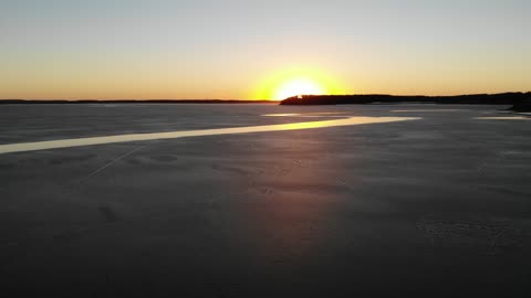 Sunset Over a Thawing Frozen Lake with Ice Patterns