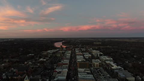 Small Town Rooftops at Dusk with a Pink Sky · Flyover