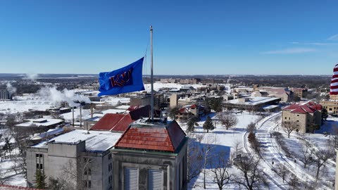 Pan Across Fraser Hall and Its Flags in Winter Snow